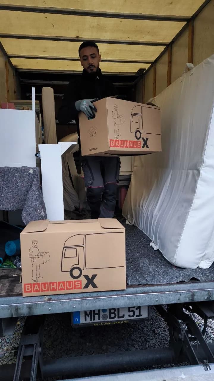 Umzugshelfer trägt Umzugskarton in den LKW
